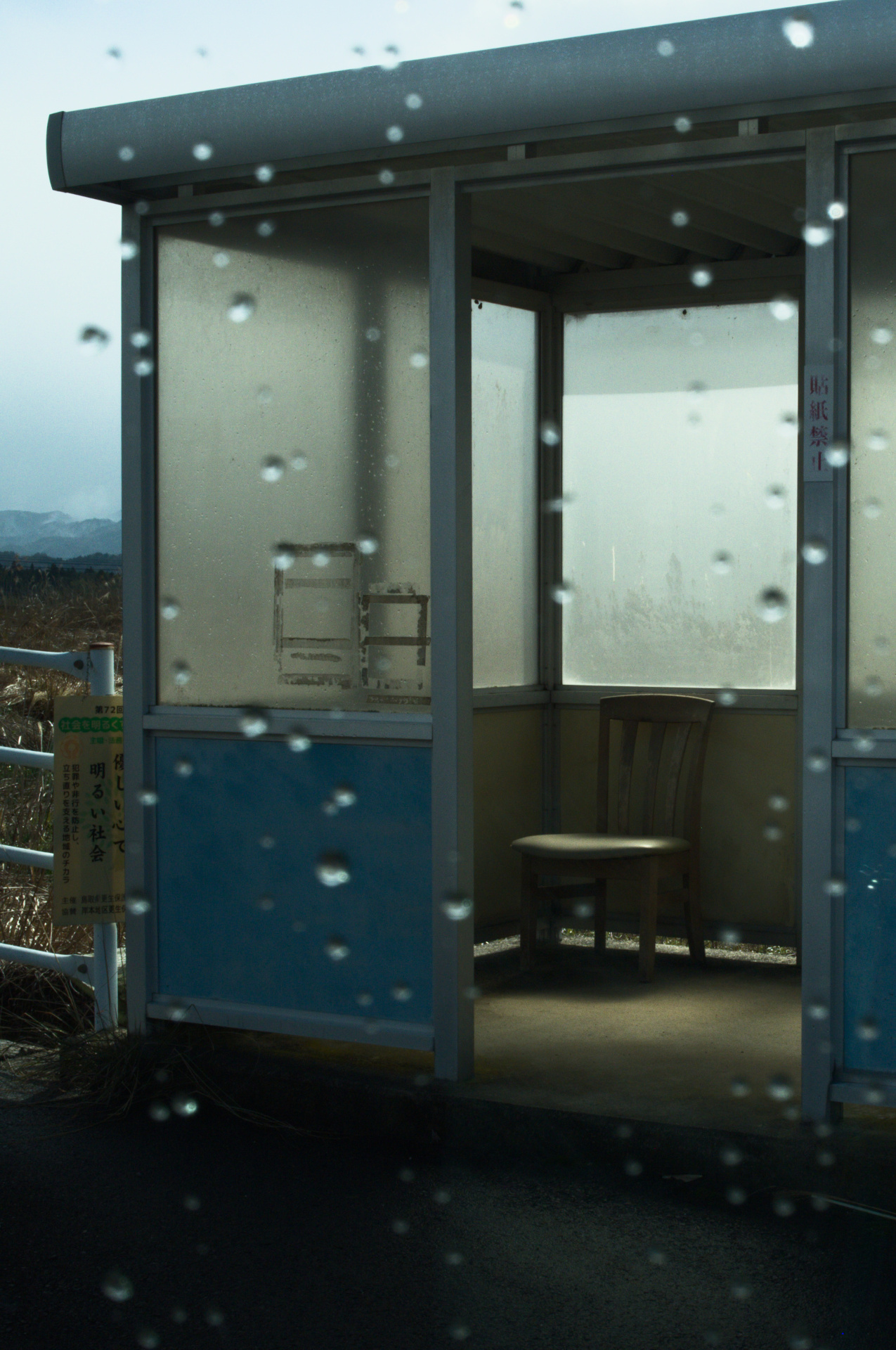 Rain-streaked train window in blue light