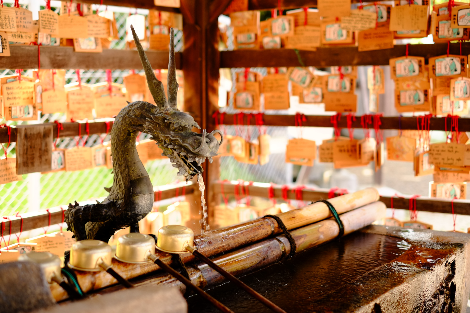 A dragon sculpture among wooden ema plaques at a shrine
