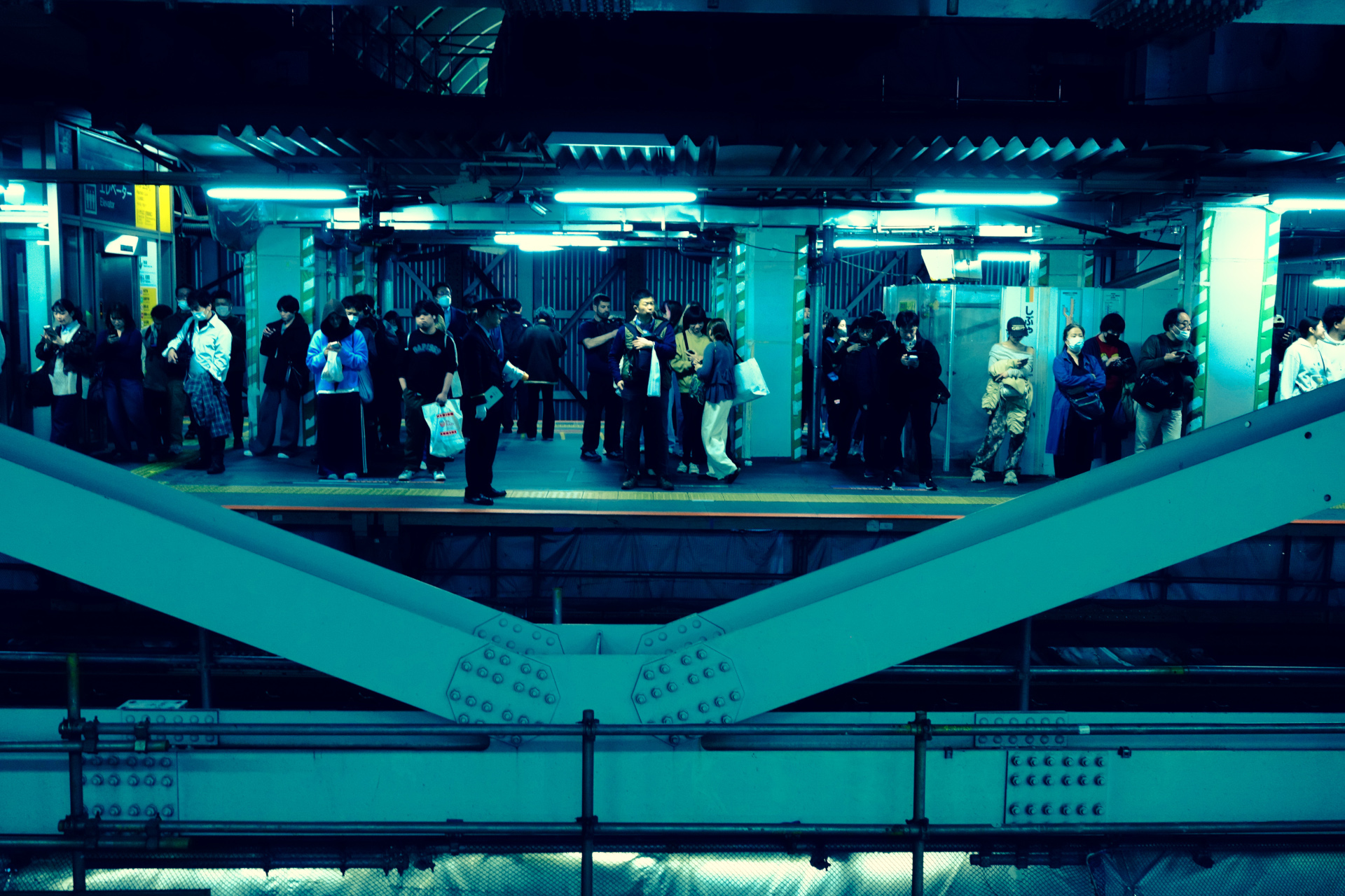 Crowd on a train platform bathed in teal light