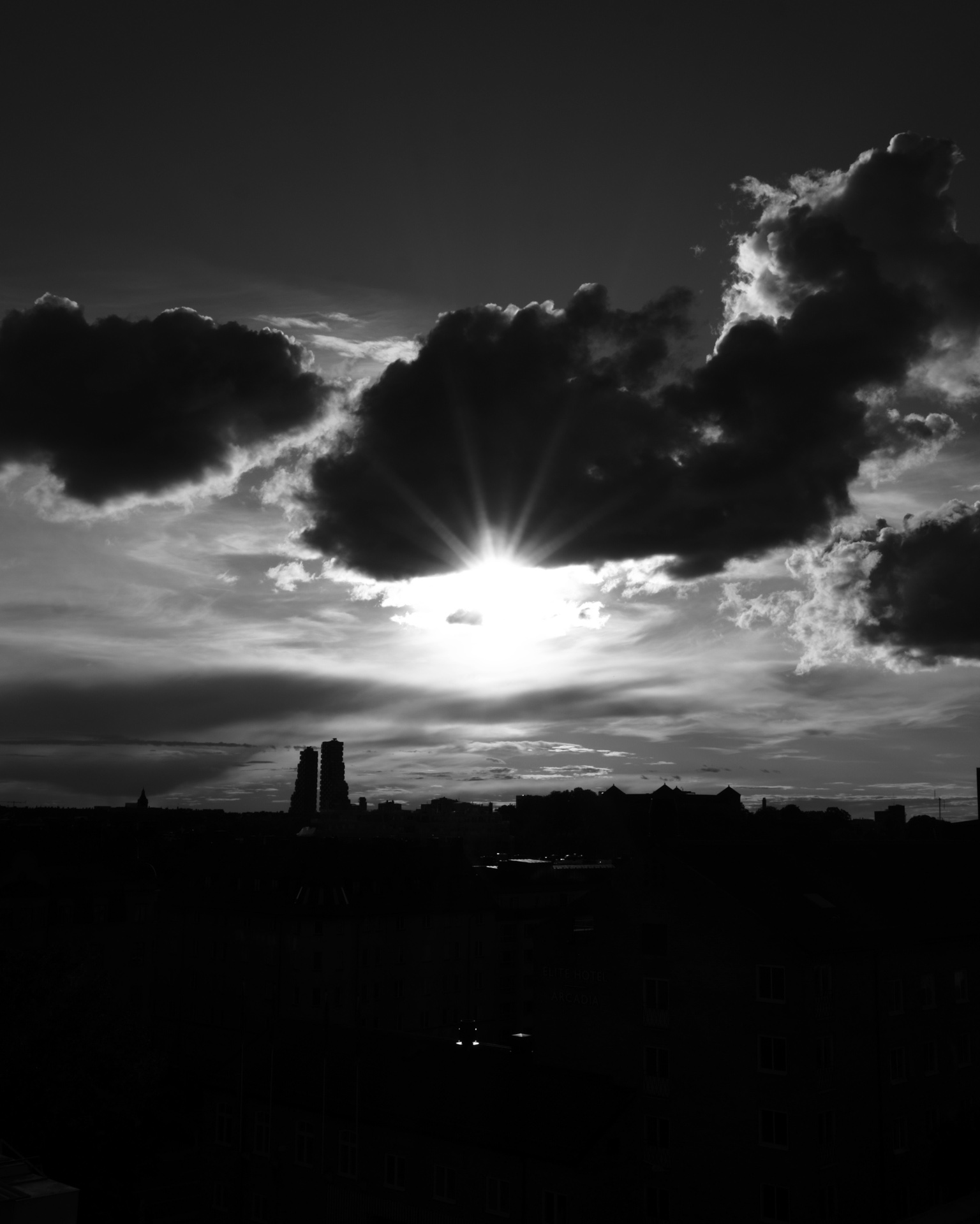 Sun breaking through dramatic clouds in black and white